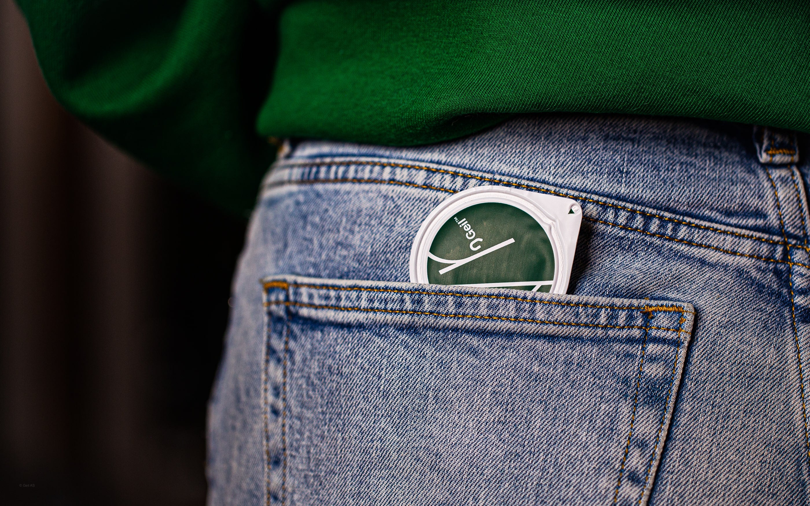 En person med en grønn genser og denim-jeans med en buttercup i baklommen.